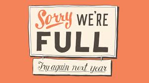 A sign that reads 'Sorry We're Full' with a smaller text beneath saying 'Try again next year', set against an orange background.