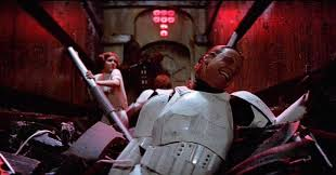 A stormtrooper lying on the ground in a dimly lit corridor, surrounded by rubble and debris, with a figure in the background.
